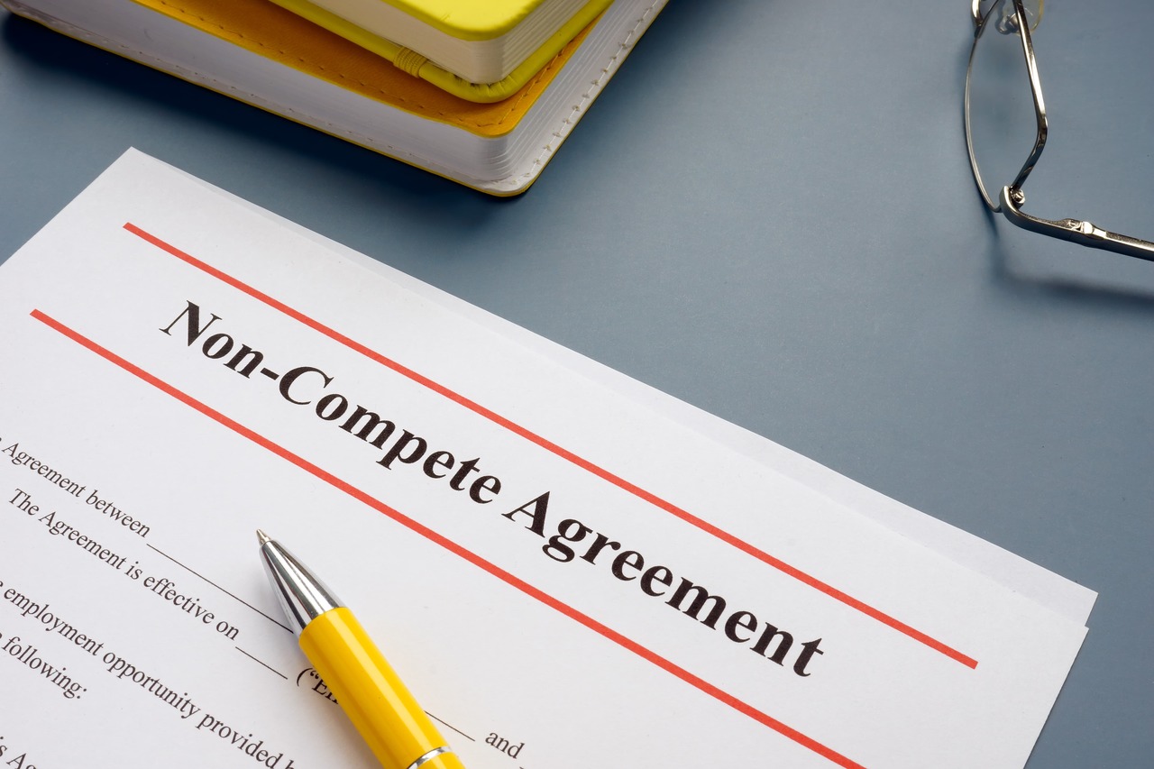 The image features a professional document titled "non-compete agreement" on someone's office desk with a yellow pen and yellow books in the background. Non-compete agreements are contracts between an employer and an employee that are typically signed at the start of their business relationship. Essentially, a non-compete agreement prohibits the employee from competing with the business directly or indirectly for a specific duration of time after their employment has ended.

This image represents our event because we'll be discussing the current state of the law of post-employment restrictive covenants and providing guidance on steps employers can take to prepare and enforce non-competition agreements to protect their customers, current employees and confidential information and trade secrets. 

 image